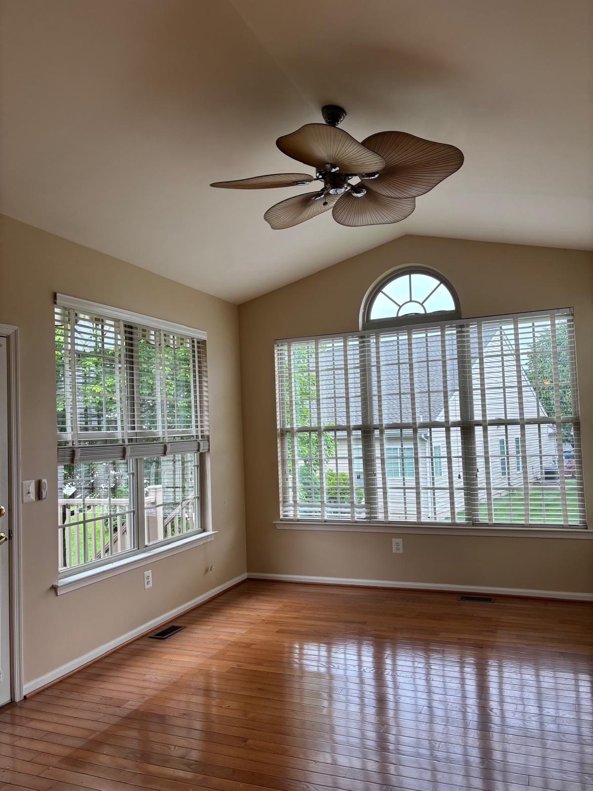 The room before the redesign — an empty sunroom with a ceiling fan and bare windows